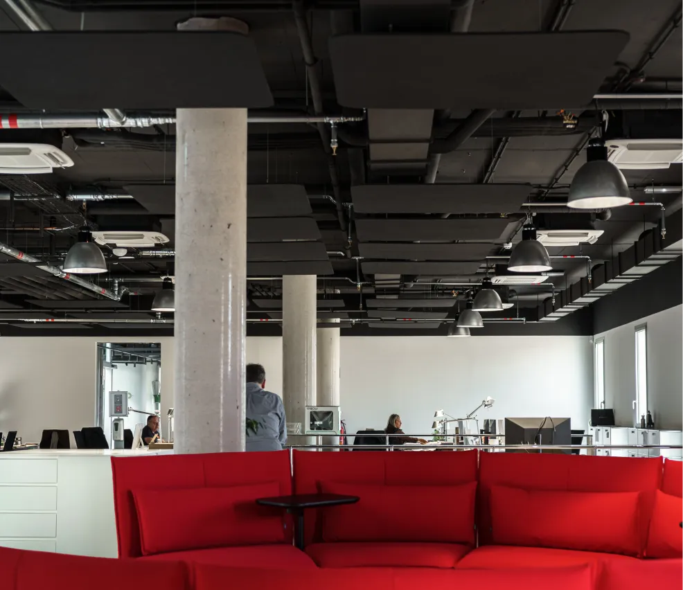 Oficina con sofá rojo y techo acústico